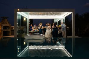 Wedding reception venue at night with illuminated white canopy and pool area.