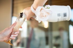 Hands pouring champagne into multiple glasses during wedding celebration.