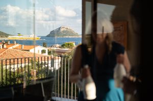 Scenic Mediterranean coastal town view from a terrace balcony on sunny day.