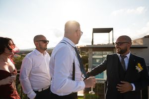 Wedding guests mingling on outdoor terrace during daytime celebration.
