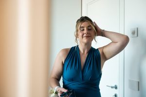Person in navy blue dress preparing for formal event in bright room.