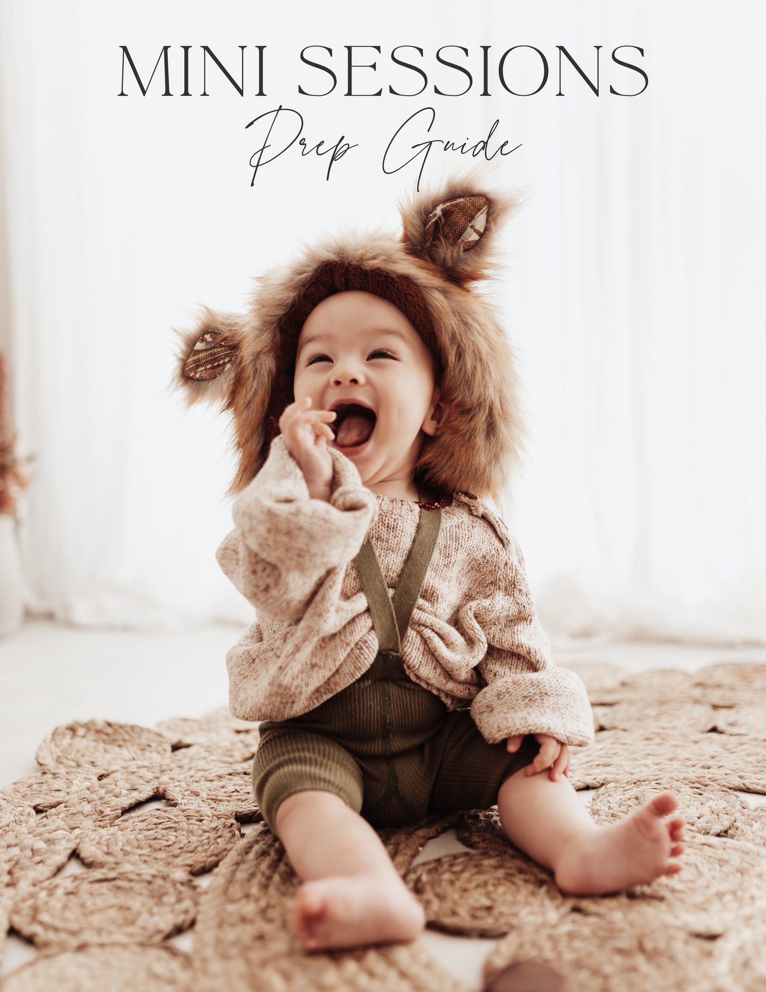 A small child in a cozy sweater and overalls sits on a beige carpet while laughing joyfully with messy hair.