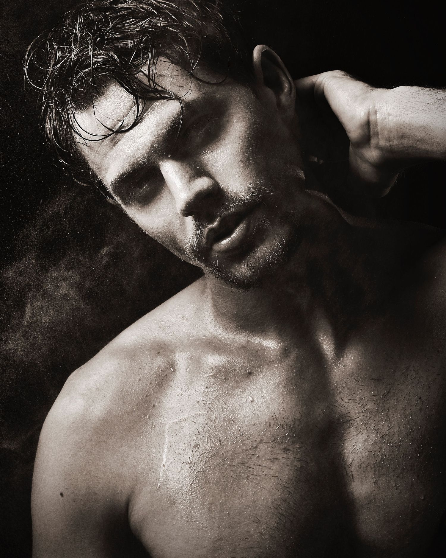 Dramatic black and white portrait in darkness with moody lighting captured in a close-up artistic style.