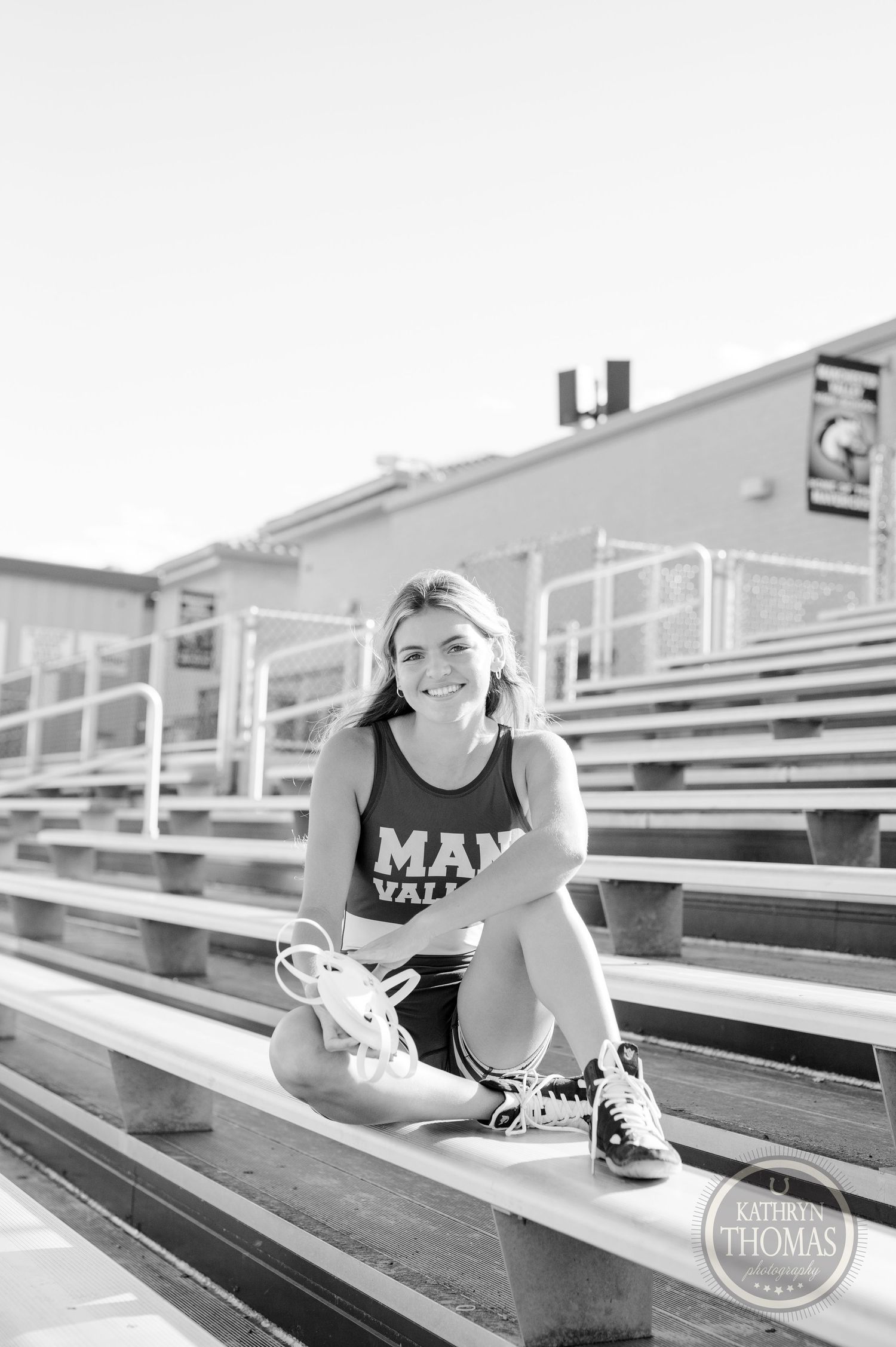 Black and white portrait of athlete sitting on stadium bleachers.