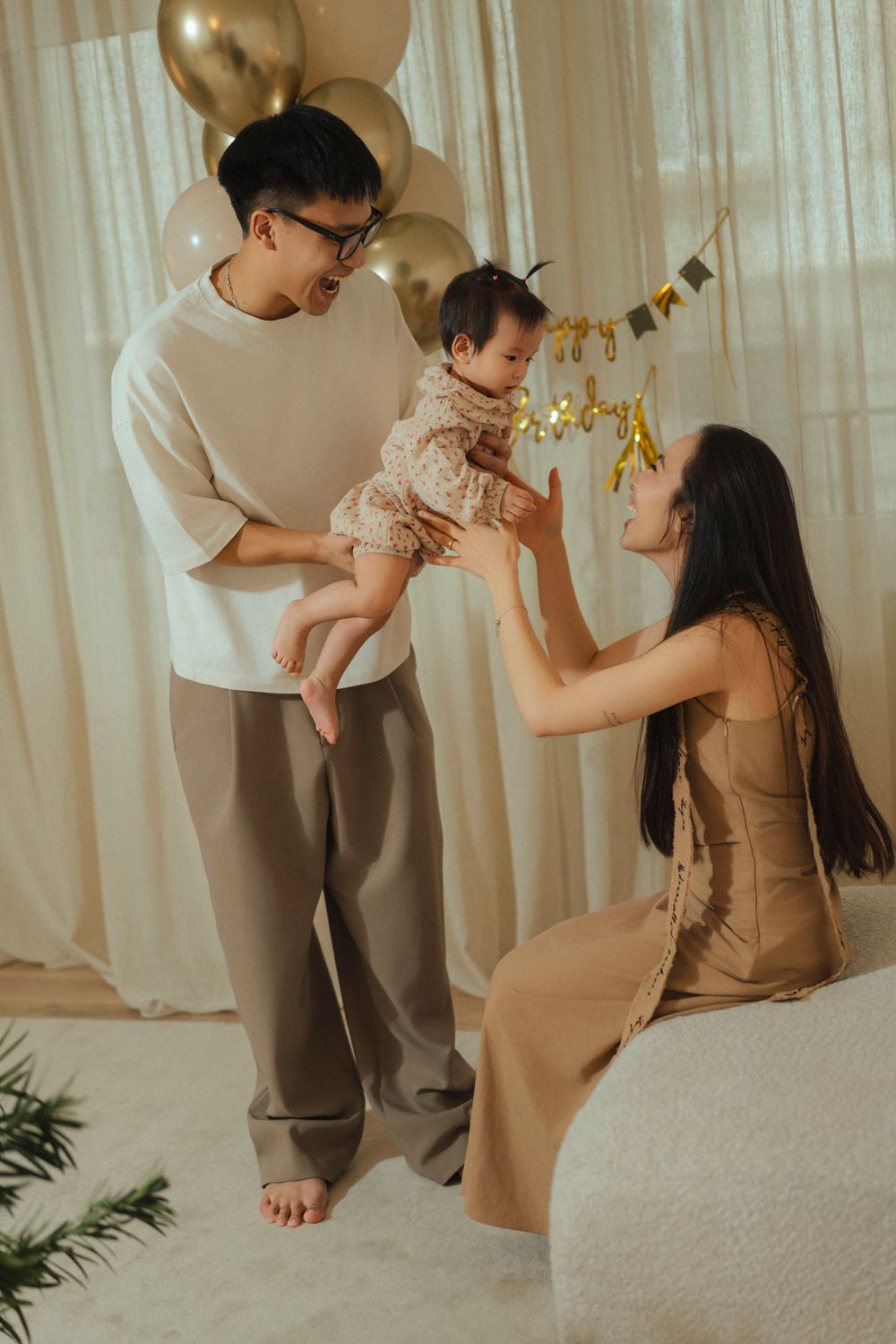 A family celebrates together with balloons and decorations in a warm, cozy indoor setting.