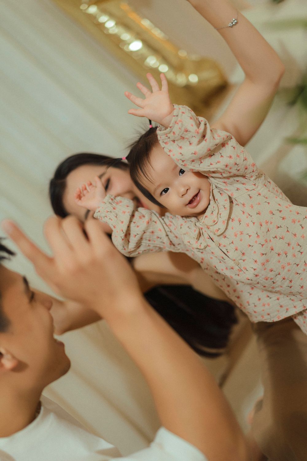 Joyful family moment captured in warm indoor lighting as they play and raise their hands together.