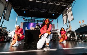 Dance group performing choreographed routine on outdoor festival stage under blue sky.