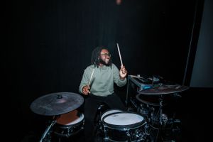A drummer performs energetically on stage with a professional drum kit setup.