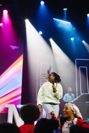 Colorful stage lights illuminate a concert performance with dynamic visual effects.