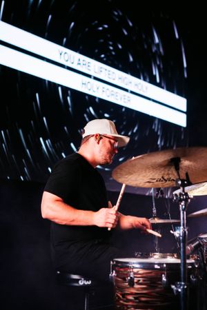 Drummer performing on stage with dramatic light trails and Zildjian cymbals.