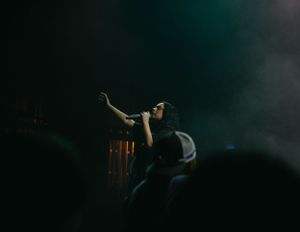 Dramatic silhouette of performer on darkened stage with teal lighting effects.
