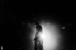 Silhouetted performer on stage backlit by bright spotlight creating dramatic atmosphere.