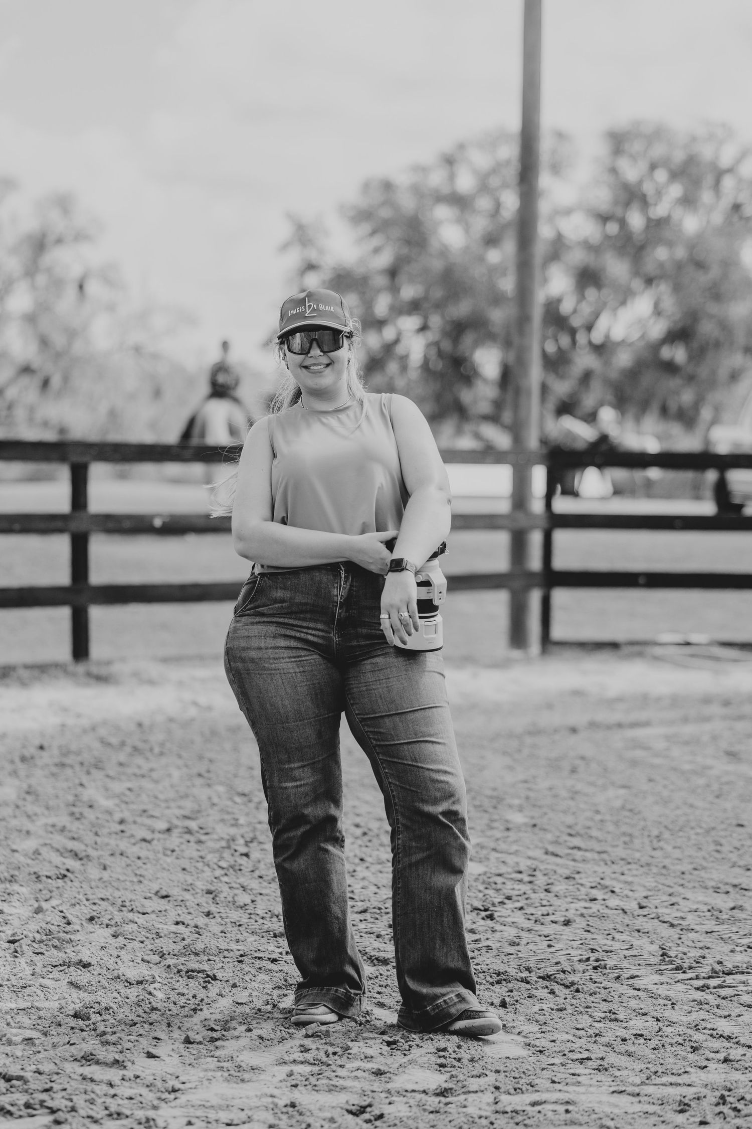 Woman in olive shirt and brown pants stands arms crossed before a large gold-framed mirror at Heartland Farm venue.