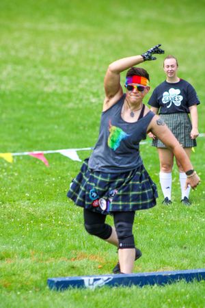 Athletes in traditional Scottish dress compete in Highland games throwing competition.