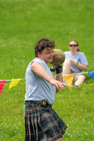 Athletes in traditional Scottish kilts compete in throwing events at Highland games.