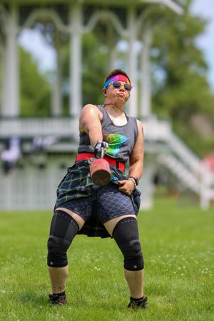 Competitor in protective gear crouching on grass field during Highland Games competition.