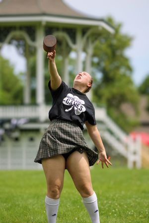 Highland Games competitor demonstrating throwing technique while wearing traditional kilt.