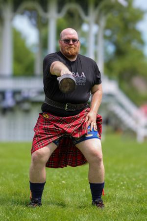 Competitor in red tartan kilt demonstrating traditional Highland Games throwing position.