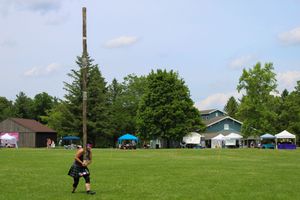 A wooden caber pole falls through the air during a traditional Scottish Highland games competition.