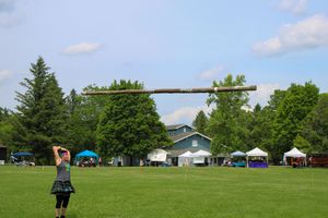 Panoramic view of a Highland games field with tents and spectators scattered across the green landscape.