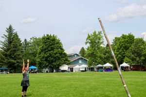 Competitors attempt to flip a large wooden pole during a traditional caber toss competition.