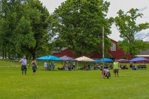 Wide shot of a Highland games event showing spectators and colorful tents on a summer afternoon.