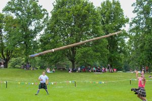 Highland games competition field with caber toss poles and spectators in background.