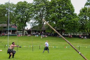 Competitors and officials gather around caber poles during highland games competition.