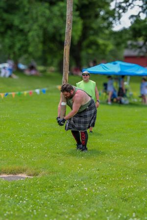 Competitor demonstrates caber toss technique during Highland games event.