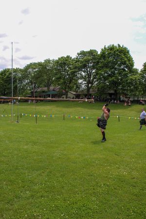 Highland games competition taking place on grassy field with colorful pennants.