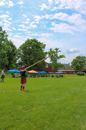 Sequence showing caber toss competition at Highland games on sunny day.