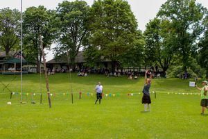 Wide view of a Highland games field showing multiple competition areas and spectator zones.