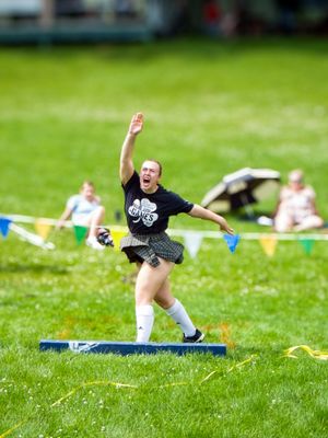 Highland Games athlete in traditional dress executing powerful throwing technique during competition.