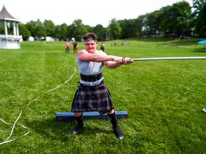 Athletes compete in traditional Highland games throwing events on a sunny grass field with a gazebo in the background.