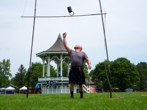 Highland games equipment and throwing area set up on a field with a white gazebo visible in the distance.