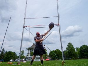 Athletes demonstrate throwing techniques during highland games competition on a green field.