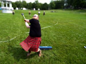Athletes in kilts perform traditional Scottish highland games throws on grass field.