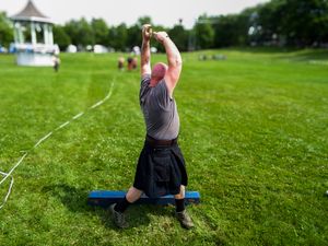 Athletes practicing weight throw techniques on a grassy field with a gazebo in the background.