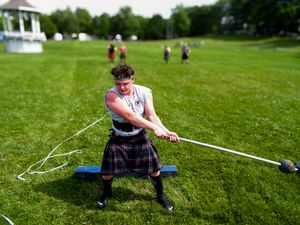 Athletes practicing traditional Highland Games throwing events on green field.