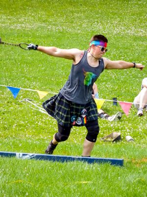 Highland Games athlete demonstrating weight throw technique in traditional kilt.