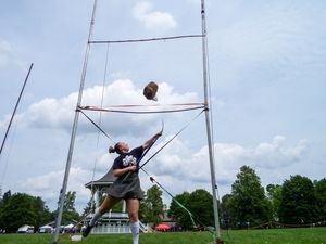 Weight throw training sequence against blue sky with gazebo in background.