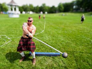 Highland Games practice session showing athletes training with weights on grass field.