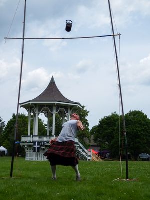 Highland Games competitor prepares to release hammer throw with gazebo visible in background.