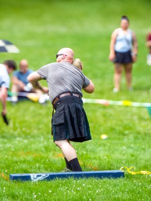 Athletes in kilts compete in throwing events at outdoor Highland games.