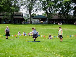 Participants and spectators gather on a grassy field for traditional Highland Games events.