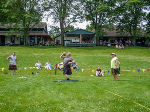 Athletes compete in traditional Scottish Highland Games on a sunny summer day.