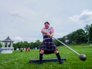Hammer thrower in traditional Scottish attire demonstrates powerful throwing stance at Highland Games.