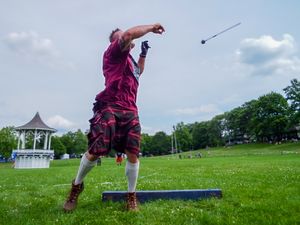 Competitor in purple attire demonstrates hammer throw technique on grass field.