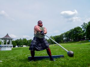 A competitor in traditional Scottish dress performs a weight throw during Highland Games.