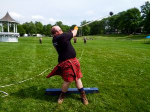An athlete in a red kilt performs a weight throw at an outdoor Highland Games event.